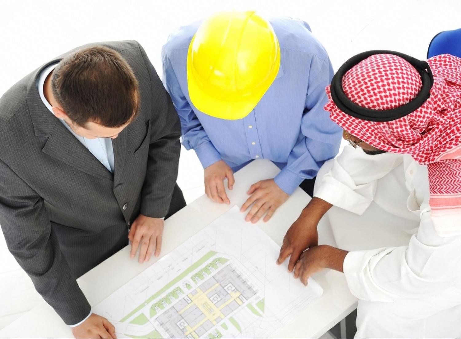 Three business partners in the UAE examining project plans and supplier documents on a table